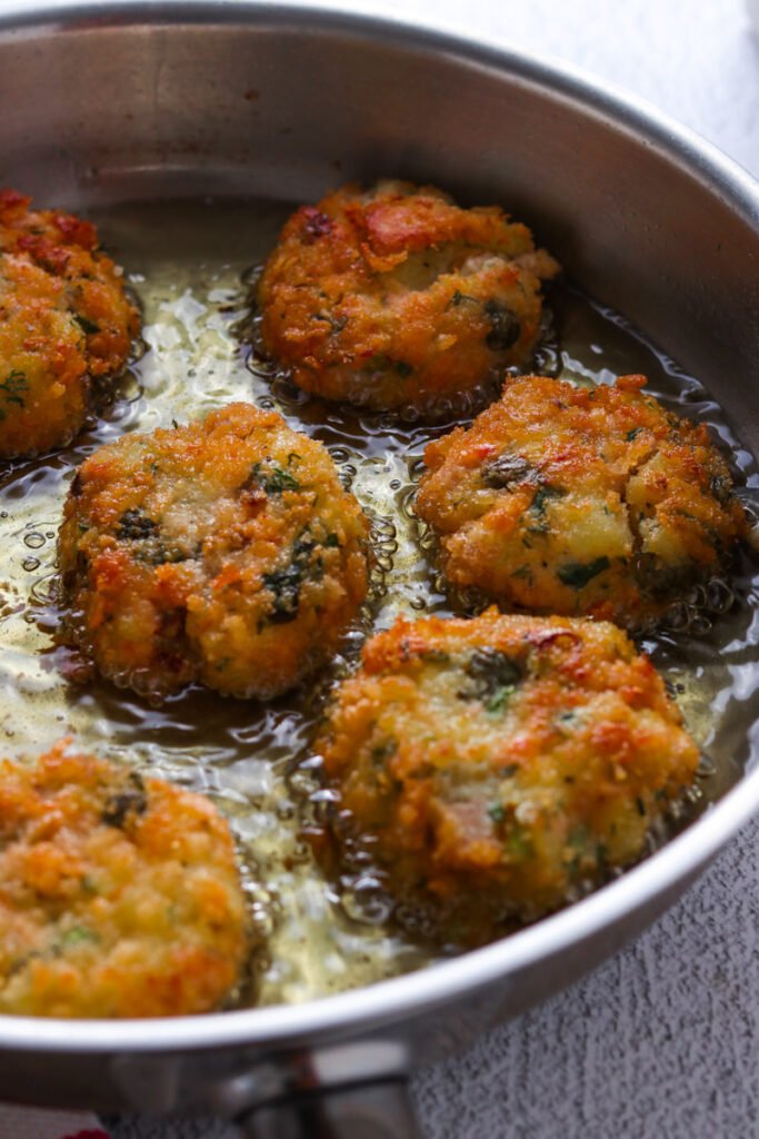 Salmon Cakes frying in oil.