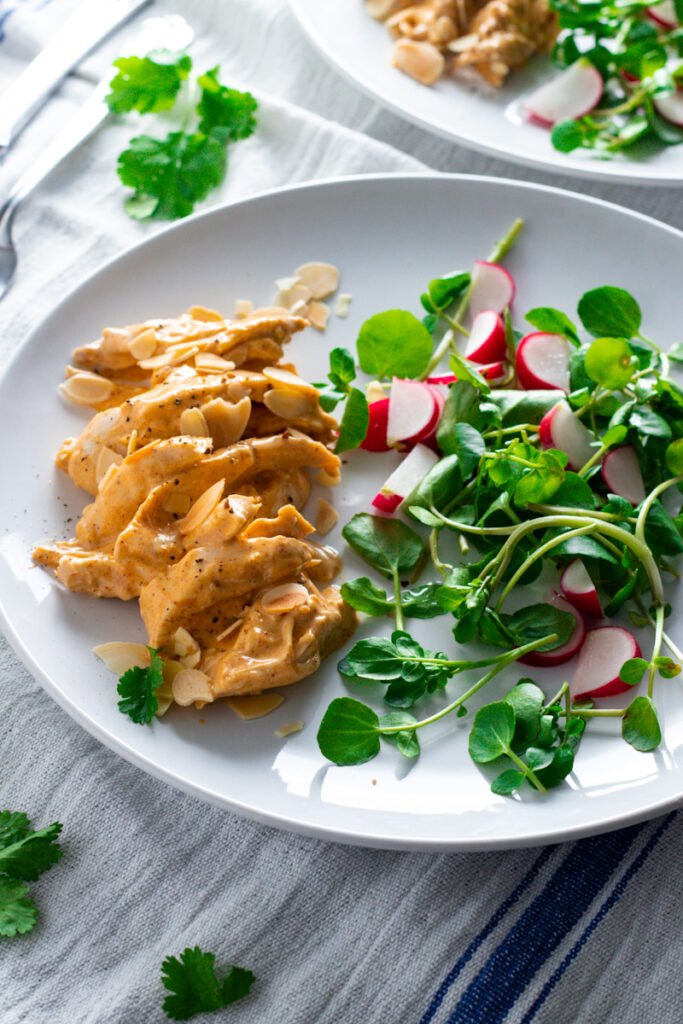 Coronation Chicken salad on a plate with watercress and radishes.