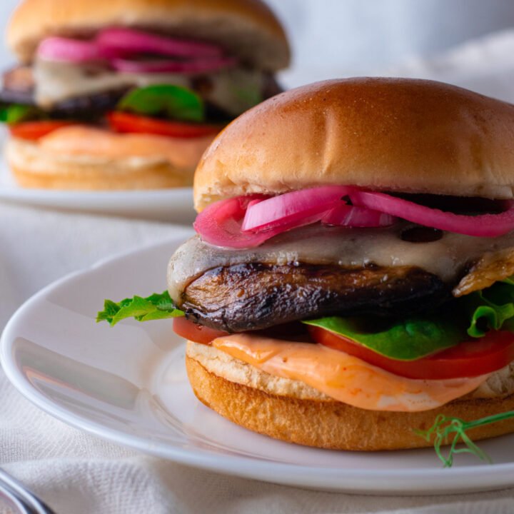 Portobello Mushroom Burgers with salad and pickled red onions on a plate.