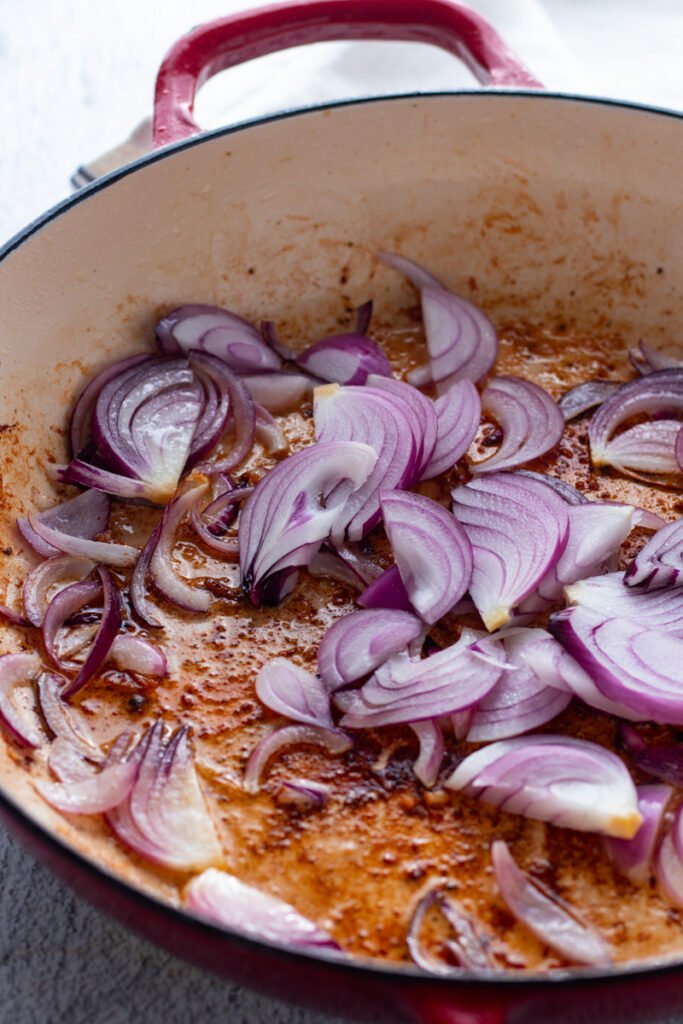Red onions cooking in a pan.