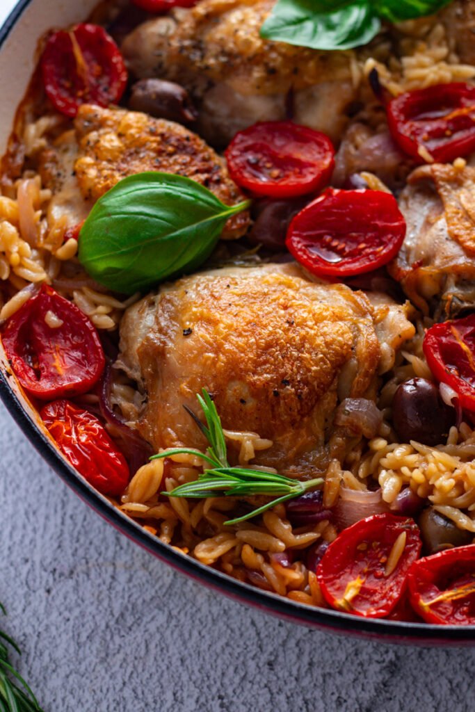 Chicken thighs and Orzo in an enamelled pan. One Pan Chicken and orzo.