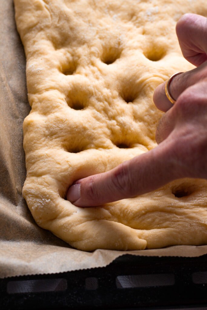 Poking holes in butterkuchen dough with finger.