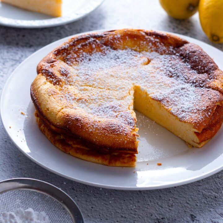 Lemon Ricotta Cake on a plate with a slice removed.