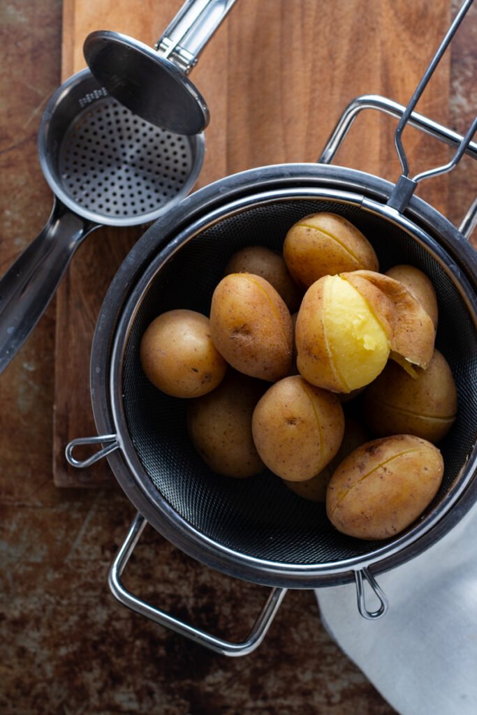 Potatoes in a pot, showing cut and peeled skin.