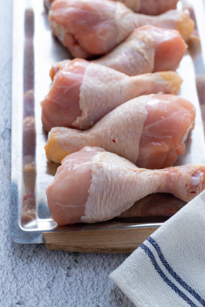 Uncooked Chicken drumsticks on a tray.