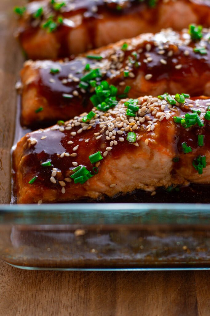 Close up of baked teriyaki glazed salmon fillets with sesame seeds and chives.
