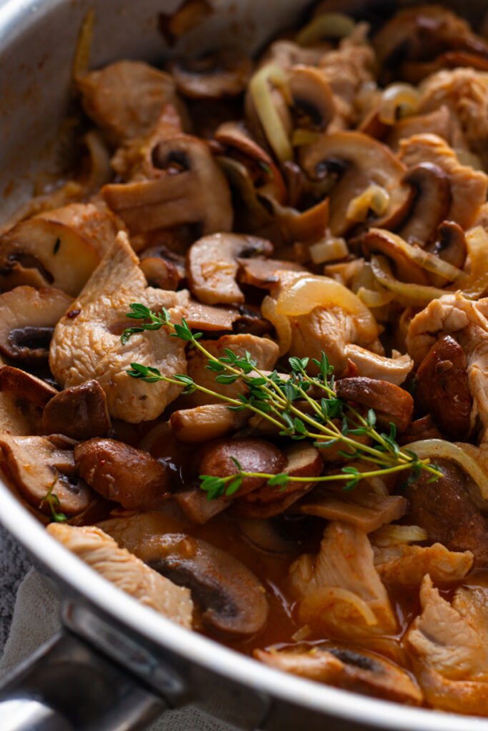 A closeup of cooked turkey stroganoff in a pan.
