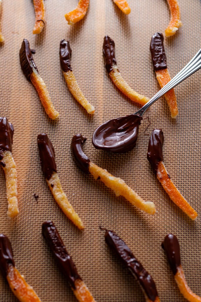 Chocolate dipped candied orange peels on a tray.