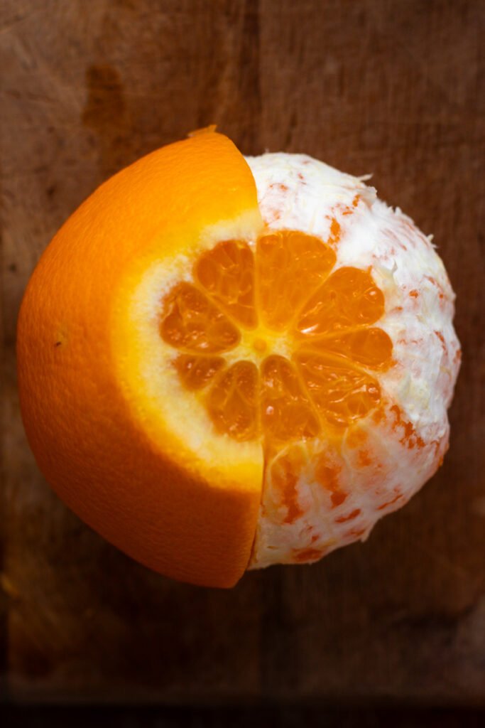 An orange with half the peel removed.
