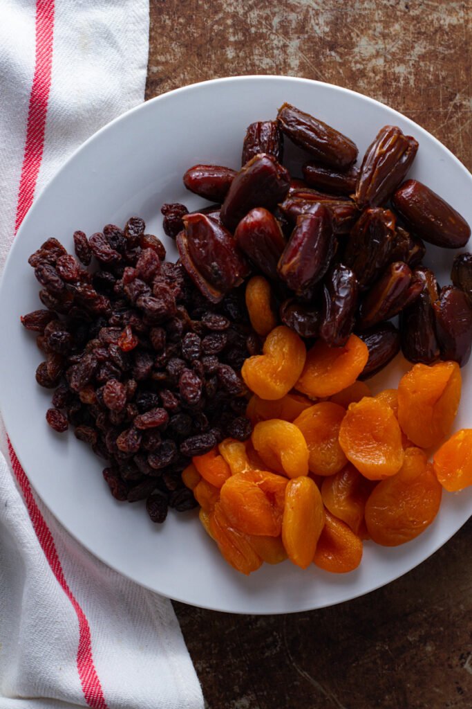Sultanas, dates and dried apricots on a plate.