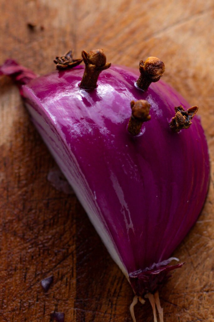 A quarter of a red onion with cloves pushed into it.