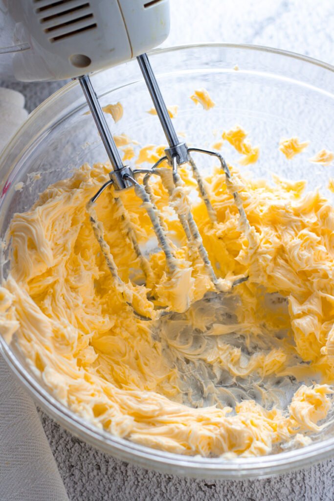 Softened butter in a bowl with an electric hand mixer.