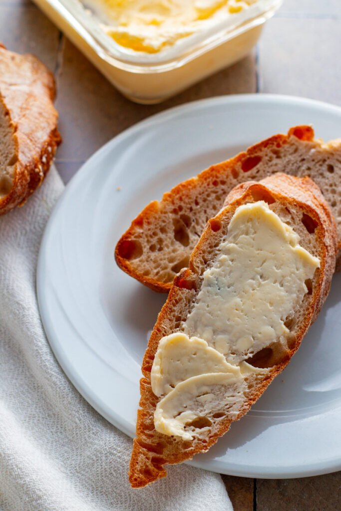 Fresh bread slices on a plate with spreadable butter.