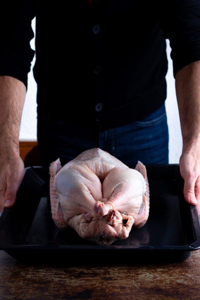 A man holding a trussed goose on a tray.