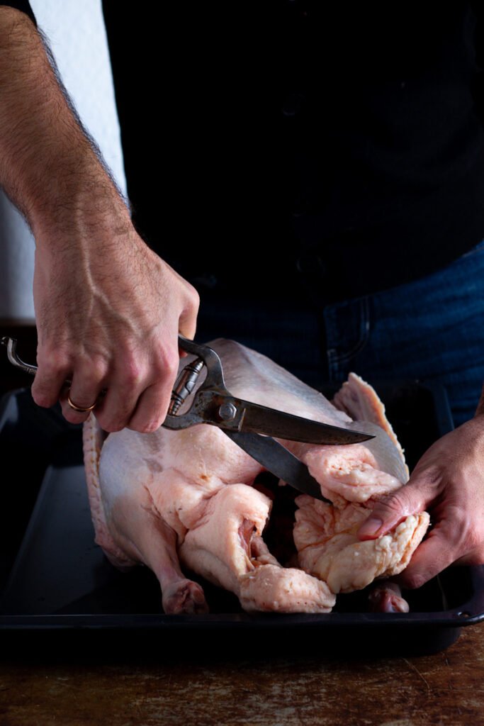 Using kitchen shears to trim excess fat off a goose.